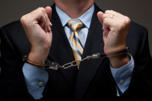 White collar criminal in a business suit and handcuffs